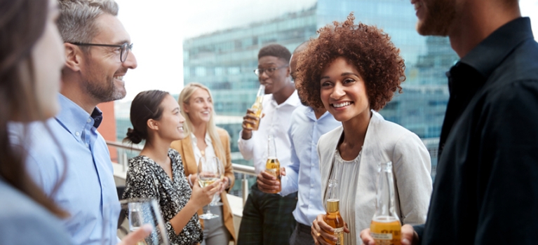 Group of multi-racial and multi-ethnic colleagues drinking beer and wine on a rooftop