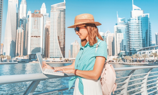 Smiling Asian woman using laptop on Dubai waterfront