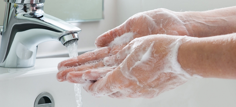 Soapy hands running under a faucet to wash them