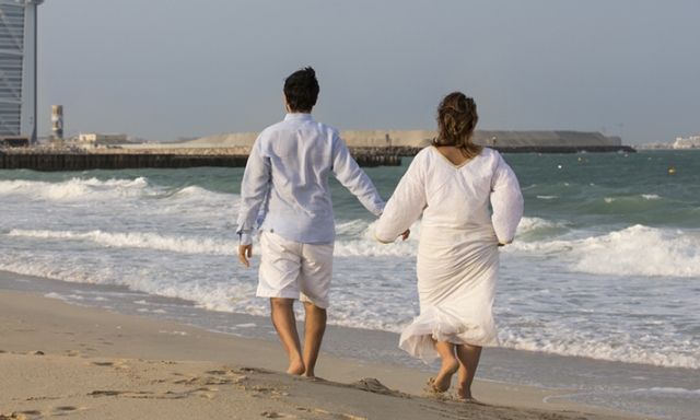 Couple holding hands while walking on beach in Dubai