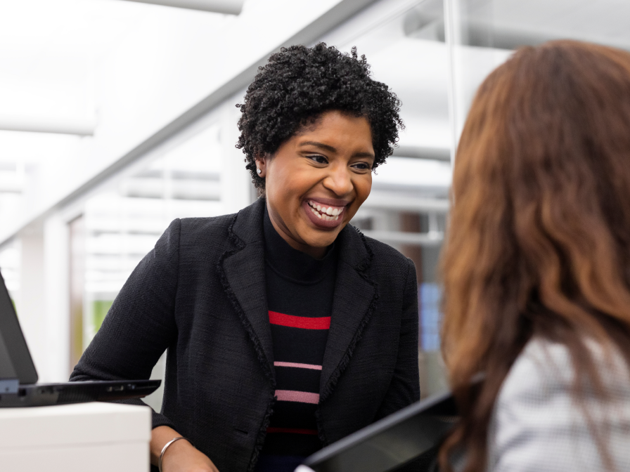 A woman smiling while talking to another person.