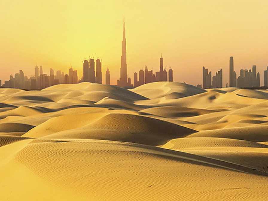 Dubai skyline with skyscrapers, at sunset, viewed from the surrounding desert.