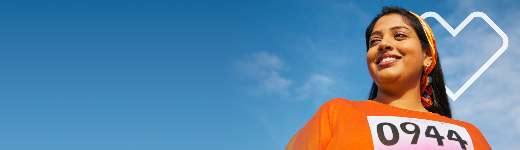 A woman with vitiligo behind another is sitting with a background of a blue sky with the Aetna heart.